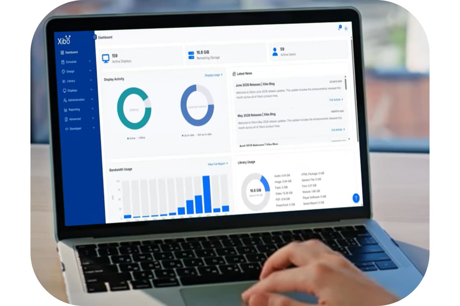 Laptop showing Xibo CMS dashboard with display activity charts and library usage stats.